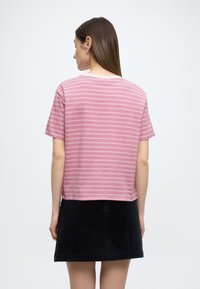 Ριγέ ροζ μπλουζάκι με κοντά μανίκια, βαμβακερό ύφασμα, άνετη γραμμή. Φορεμένο με μαύρη φούστα από κοτλέ ύφασμα, με ευθεία τελείωμα.