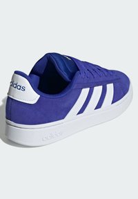 Sneaker viola in suede con dettagli bianchi, caratterizzata da tre strisce, un colletto imbottito e una suola in gomma. Marchio sul tallone.