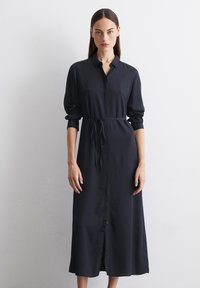 Abito a maniche lunghe di un blu navy scuro realizzato in tessuto liscio, con un'apertura frontale a bottoni, colletto, cintura in vita e orlo fino a metà polpaccio.