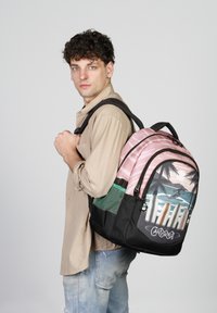 Mochila negra y rosa con diseño de palmera, bolsillo lateral de malla y texto gráfico. Diseñada con correas ajustables y cierre de cremallera.