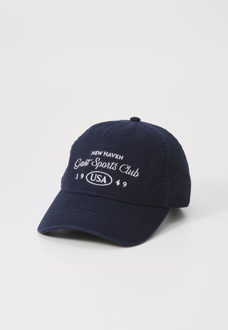Navy blue cotton baseball cap with embroidered text "New Haven Gant Sports Club 1949 USA." Features a curved brim and adjustable strap at the back.