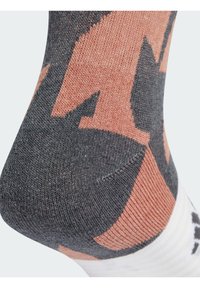 Calzino multicolore con una miscela di tonalità grigie e pesca, lavorato a maglia testurizzata e un prominente motivo geometrico. Tessuto morbido con bordo bianco.