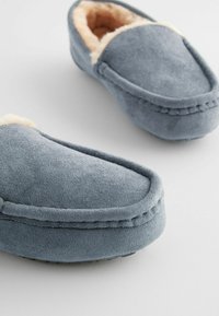 Grau Wildlederschuhe mit weicher, hellbeiger Fütterung, abgerundeter Spitze und hervorgehobenem Nahtdetail entlang der Kanten. Bequeme, strukturierte Oberfläche.