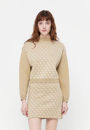 Maglione beige a maglia e gonna coordinata con motivo a rombi in beige più chiaro. Polsini e colletto a coste con una silhouette aderente.