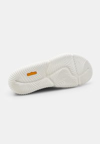 Fehér cipőtalp, texturált barázdákkal és mintákkal. Középen kiemelkedő, narancssárga "Float Activ" felirattal.