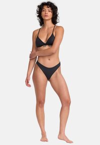 Čierny bikiny set s trojuholníkovým vrchom a tenkými ramienkami, a s nohavičkami s nízkym pásom. Hladká tkanina s minimálnym brandingom a elegantný dizajn.