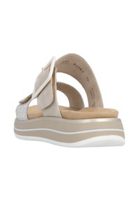 Sandale beige avec une large bride, des accents texturés et une semelle rembourrée. Elle présente une grande boucle décorative et un détail discret d'imprimé animal.