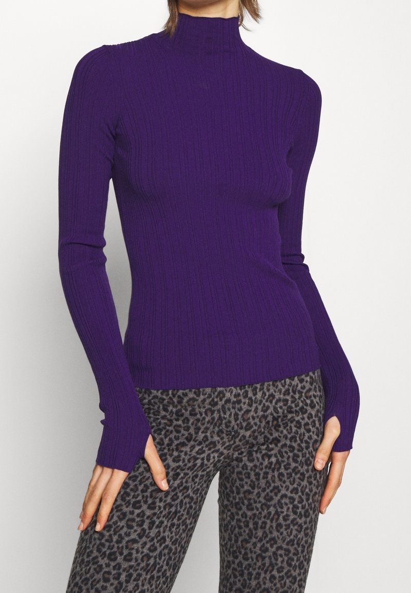 Lila ribbad långärmad topp med hög krage och tumhål ärmar, tillsammans med grå leggings i leopardmönster. Mjuk, stretchig tyg.