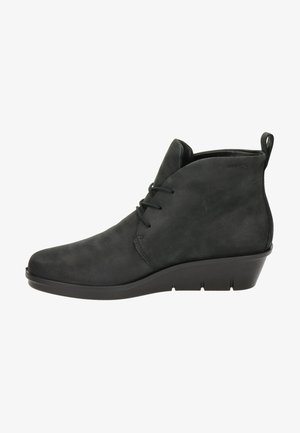 Bottines noires à bout arrondi, en daim doux. Dotées d'un talon compensé bas et d'un design à lacets. Texture lisse et détails minimaux.