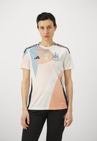 Hvid sports jersey med abstrakte pastel geometriske mønstre i fersken, blå og grå. Har FIFA-logo og det spanske flagsemblem. Sorte accenter.