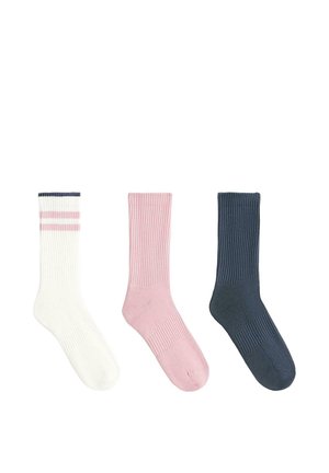 Trois chaussettes montantes côtelées étalées à plat : une blanche avec des rayures roses, une rose uni, et une bleu marine uni.