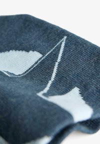 Tessuto blu lavorato a maglia con un motivo geometrico in blu chiaro, dalla consistenza morbida e una leggera lucentezza, piegato in un primo piano.