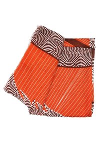 Tessuto arancione con motivi a strisce bianche e accenti circolari marroni. I bordi sono sfrangiati, mostrando distinte variazioni di colore e texture.