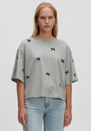 Grijze oversized T-shirt van katoen, met zwarte kruisborduursel. Korte mouwen met een relaxte pasvorm en een ronde hals.