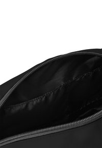 Borsa nera in nylon con apertura a zip, caratterizzata da un interno liscio e una piccola tasca laterale per ulteriore spazio di archiviazione.