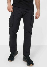 Svarte cargo bukser med flere sidelommer, laget av lett stoff. Designet inkluderer rett snitt og elastiske mansjetter ved anklene.