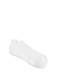 Une chaussette blanche simple à la cheville en tissu côtelé, présentée sur fond blanc, avec un bord élastique et une zone lisse au niveau des orteils.