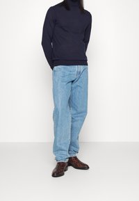 Námořnický rolák, světle modré džíny rovného střihu a hnědé vzorované boty. Jednoduchý design s volným střihem z příjemné směsice bavlny.