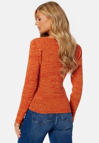 Geribbelde, lange mouwen trui in feloranje, met een slim fit ontwerp, textuurstof en een ronde halslijn. Gekocht met een blauwe spijkerbroek.