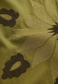 Geweven textiel in olijfgroen, met bloemmotieven in goud en donkerbruin, met gevarieerde texturen en gedetailleerde stiksels.