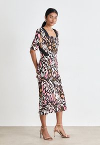 Multicolored dress featuring a butterfly print in pink, black, and orange. It has a square neckline and short sleeves, made from soft fabric.