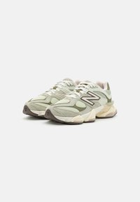 New Balance-sko i lysegrønn mesh og semsket skinn, med en tykk lys beige såle og mørkebrune detaljer.