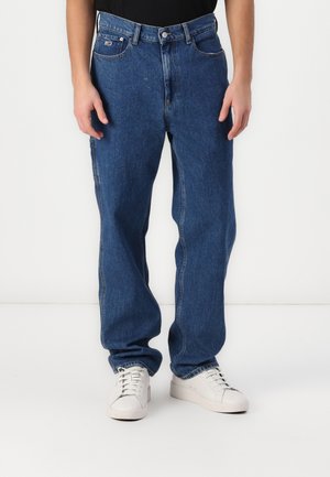 Lichtblauwe denim jeans met een rechte pasvorm, vijf zakken en een vervaagde afwerking. Bevat een merkpatch op de tailleband. Gecombineerd met witte sneakers.