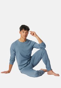 Blauwe katoenen loungewear set met lange mouwen en taps toelopende broek. Zachte textuur, relaxte pasvorm en subtiel gemêleerd patroon.