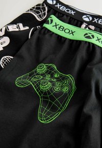 Black shorts with a green Xbox logo waistband and a green geometric controller design, featuring smooth fabric and a casual fit.