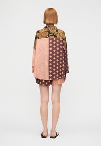 Τυπωμένο πουκάμισο σε στυλ κιμονό σε μαύρο, πορτοκαλί, ροζ και καφέ με περίτεχνα μοτίβα· συνοδεύεται από ταιριαστά σορτς. Λείο ύφασμα, άνετη εφαρμογή.