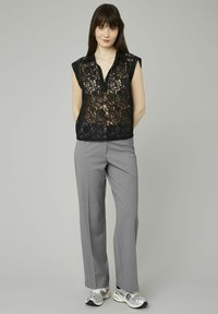 Haut en dentelle noire avec des manches courtes, design col, associé à un pantalon ajusté gris clair et des baskets grises. Texture lisse, motif floral.