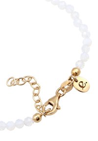 Weiße facettierte Perlen mit einem goldenen Karabinerverschluss und Kettenverlängerung, versehen mit einem kleinen Anhänger mit einem Symbol. Glatte Textur und glänzende Oberfläche.