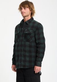Flannel shirt with a dark green and black check pattern, featuring a button-up front, two breast pockets, and a classic collar.