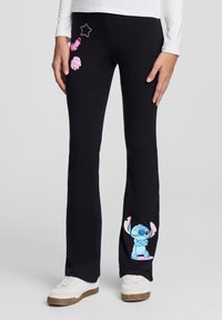 Leggings neri con grafiche giocose di personaggi in rosa e blu, con un design cucito e una forma svasata della gamba. Vestibilità casual con cintura elastica.