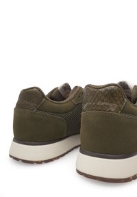 Olivovo zelené tenisky s kombináciou semišu a texturovanej sieťoviny, s bielou gumovou podrážkou a hnedými akcentmi na spodnej strane.