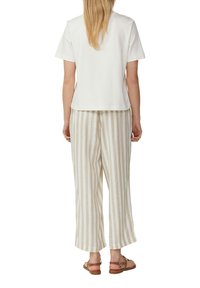 Witte top met korte mouwen, gecombineerd met beige en witte verticaal gestreepte wijde broek, bekend om de zachte textuur en relaxte pasvorm.