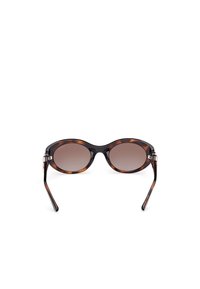 Ochelari de soare cu rame de broască țestoasă, lentile ovale, nuanță de maro în gradient și temple negre elegante. Accente de hardware argintiu pe laterale.