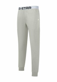 Lichtgrijze sweatpants met een witte elastische tailleband met daarop zwarte "G-STAR" tekst. Boorden bij de enkels, gladde textuur, casual ontwerp.