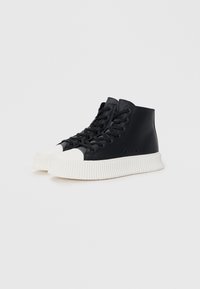High-top sneakers made of black material with white rubber soles. Features include round toe, lace-up design, and ridged sole.