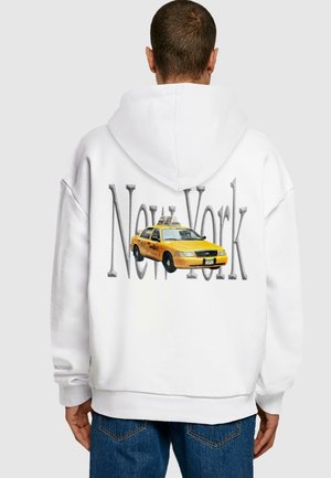 Hvid hoodie med et grafik af en gul taxa og teksten "New York" i store grå bogstaver på ryggen. Blødt materiale, afslappet pasform.