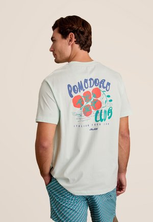 Lichtgroene T-shirt met korte mouwen met een kleurrijke "Pomodoro Club" graphic op de achterkant, met tomaten en bladachtige accenten.