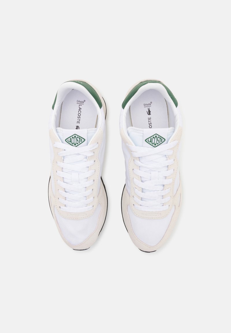 Lacoste-Sneaker aus weißem Mesh und cremefarbener Wildleder mit grünen Akzenten. Verfügt über eine gepolsterte Sohle und ein klassisches Schnürdesign.