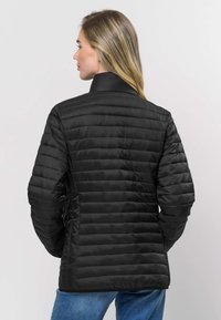 Svart vadderad jacka med ståkrage och quiltad design. Snygg, slät textur med åtsittande form och dragkedjeförsedda sidofickor.