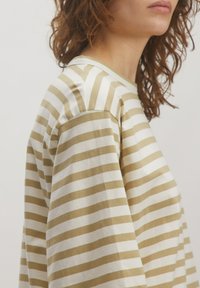 Gestreepte langemouwshirt in crèmekleur en lichtbeige, met een ronde halslijn, een ontspannen pasvorm en zachte katoenen stof. Zichtbare steekdetails.