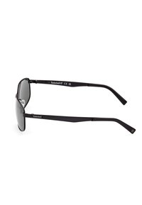 Gafas de sol tipo aviador negras con lentes grises. La montura de metal presenta un logo en las patillas. Incluye almohadillas nasales para mayor comodidad.