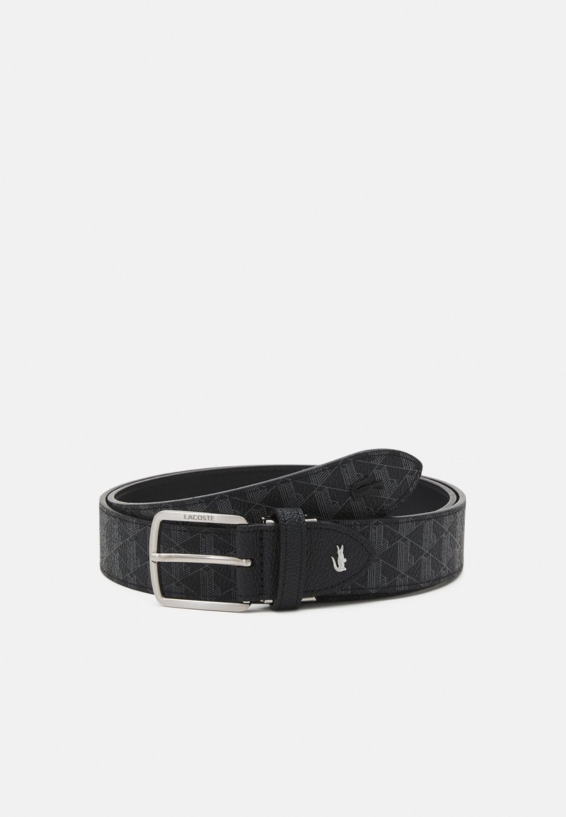 Ceinture en cuir noir avec motif géométrique, boucle rectangulaire en argent gravée "Lacoste" et petit logo crocodile en argent proche de la boucle.