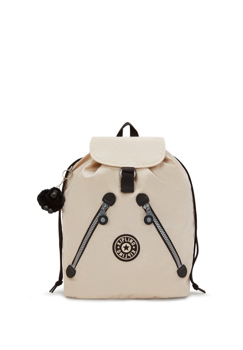Zaino in nylon beige con chiusura a pattina, hardware nero, doppie cerniere e un logo rotondo. Include un portachiavi di una scimmia pelosa attaccato.