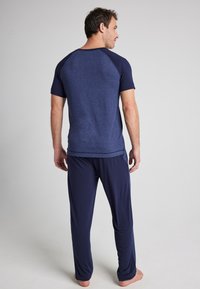 Mörkblå atletisk pyjamas set med en t-shirt med korta ärmar, kontrasterande raglanärmar, och matchande byxor, båda i mjukt, lätt tyg.