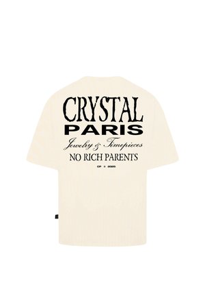 Beige oversize tričko s krátkým rukávem. Na zadní straně je černý potisk s nápisem: "CRYSTAL PARIS Jewelry & Timepieces NO RICH PARENTS."