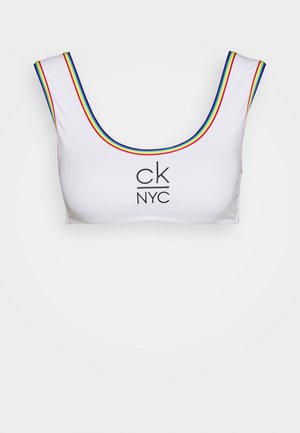 Biely crop top s okrúhlym výstrihom, s farebnými prúžkami pozdĺž okrajov a centrálnym čiernym logom "ck NYC". Hladká štruktúra látky.